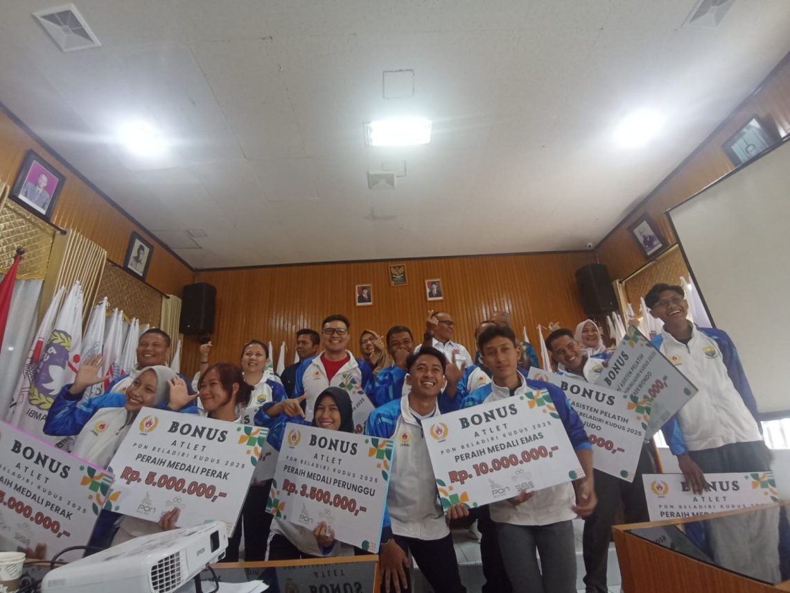 Para atlet bela diri Jambi bersama Ketua Umum KONI Provinsi Jambi, Mat Sanusi, berpose usai menerima bonus penghargaan dalam acara tasyakuran dan penyambutan atlet PON Bela Diri Jambi, Kamis (30/10/2025). (Dok: Rahmat)