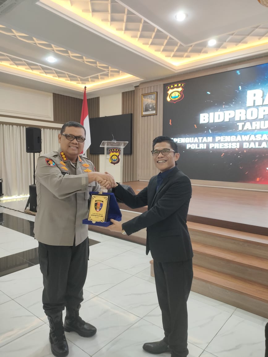 Kepala Perwakilan Ombudsman RI Provinsi Jambi, Saiful Roswandi, menerima plakat penghargaan dari perwakilan Polda Jambi usai memberikan materi Post Assessment di Aula Siginjai Polda Jambi, Jumat 14 November 2025. (Dok: Rahmat)