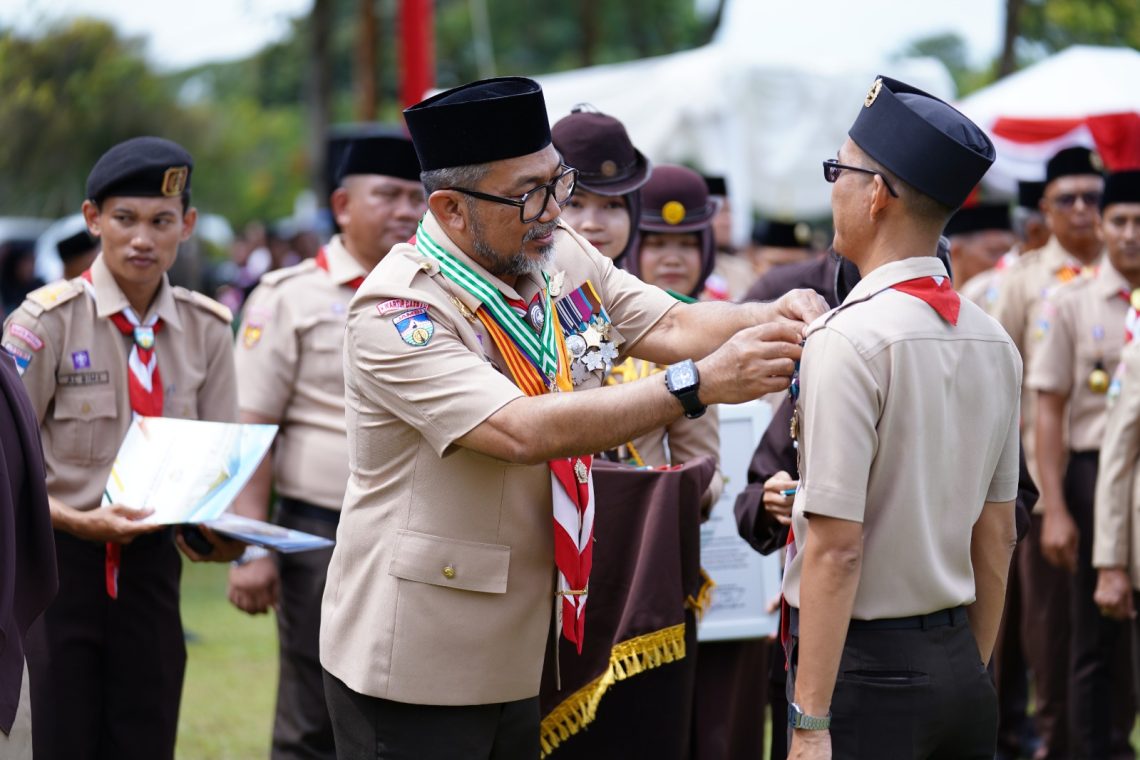 Sekda Sudirman saat menyematkan pin kepada anggota Pramuka mengikuti Apel Besar Hari Pramuka ke-64 di Lapangan Kantor Bupati Tanjung Jabung Timur, Rabu (19 November 2025). (DOk: Diskominfo Provinsi Jambi)