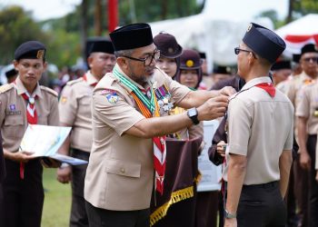 Sekda Sudirman saat menyematkan pin kepada anggota Pramuka mengikuti Apel Besar Hari Pramuka ke-64 di Lapangan Kantor Bupati Tanjung Jabung Timur, Rabu (19 November 2025). (DOk: Diskominfo Provinsi Jambi)