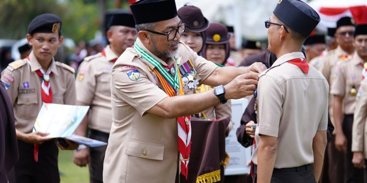 Sekda Sudirman saat menyematkan pin kepada anggota Pramuka mengikuti Apel Besar Hari Pramuka ke-64 di Lapangan Kantor Bupati Tanjung Jabung Timur, Rabu (19 November 2025). (DOk: Diskominfo Provinsi Jambi)