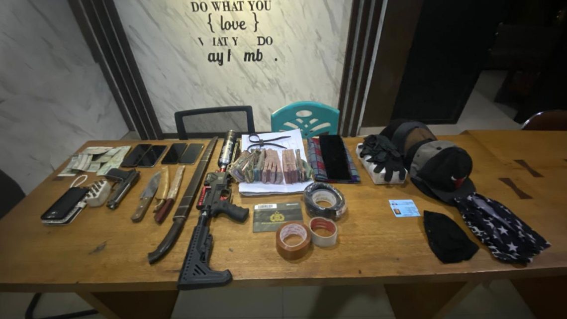 Barang bukti kasus perampokan bersenjata yang berhasil diamankan Sat Reskrim Polres Merangin, terdiri dari uang tunai, telepon genggam, kendaraan, perlengkapan penyamaran, dan senjata tajam. Foto diambil di Mapolres Merangin, Kamis (20/11/2025). (Dok: Rudi)