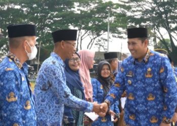 Bupati Merangin M. Syukur menyerahkan bantuan tali asih kepada pensiunan ASN dan uang duka kepada ahli waris anggota Korpri pada Apel Kesiapsiagaan HUT Korpri ke-54 di halaman Kantor Bupati Merangin, Senin (01/12/2025). (Dok: Rudi)