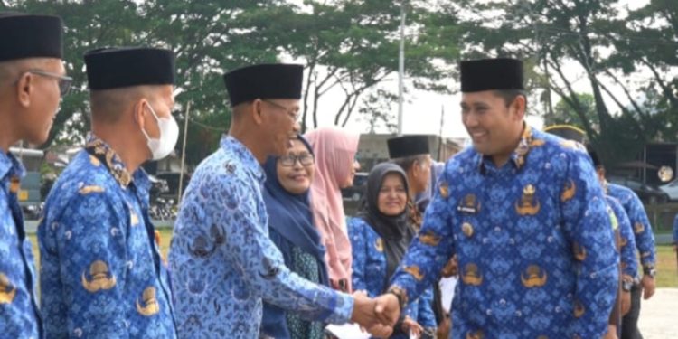 Bupati Merangin M. Syukur menyerahkan bantuan tali asih kepada pensiunan ASN dan uang duka kepada ahli waris anggota Korpri pada Apel Kesiapsiagaan HUT Korpri ke-54 di halaman Kantor Bupati Merangin, Senin (01/12/2025). (Dok: Rudi)