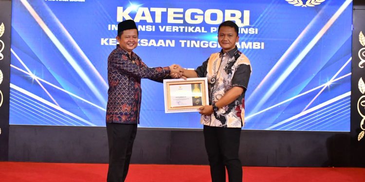 Koordinator Bidang Intelijen Kejati Jambi Dede Muhammed Yasin menerima penghargaan predikat Informatif pada Penganugerahan Keterbukaan Informasi Badan Publik Se-Provinsi Jambi Tahun 2025 di Rumah Dinas Gubernur Jambi, Selasa (17/12/2025). (Dok: Rudi)