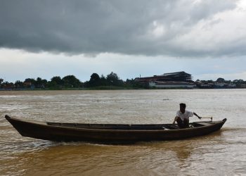 Warga menggunakan perahu untuk melintasi kawasan pesisir Tanjab Timur di tengah peringatan potensi cuaca ekstrem, Senin (1/12/2025). (Dok: Rudi)