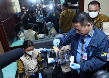 Petugas BNN bersama Bea dan Cukai serta Imigrasi menunjukkan barang bukti liquid vape dan kemasan sachet minuman energi yang mengandung narkotika hasil pengungkapan jaringan internasional di Bandara Soekarno-Hatta, Tangerang, Banten. (Dok: Humas BNN RI)