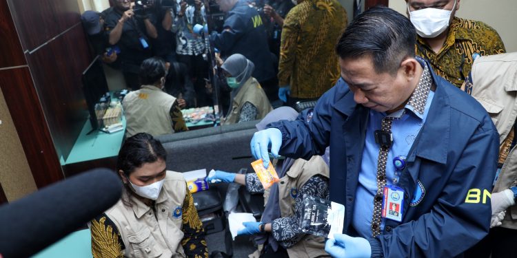 Petugas BNN bersama Bea dan Cukai serta Imigrasi menunjukkan barang bukti liquid vape dan kemasan sachet minuman energi yang mengandung narkotika hasil pengungkapan jaringan internasional di Bandara Soekarno-Hatta, Tangerang, Banten. (Dok: Humas BNN RI)