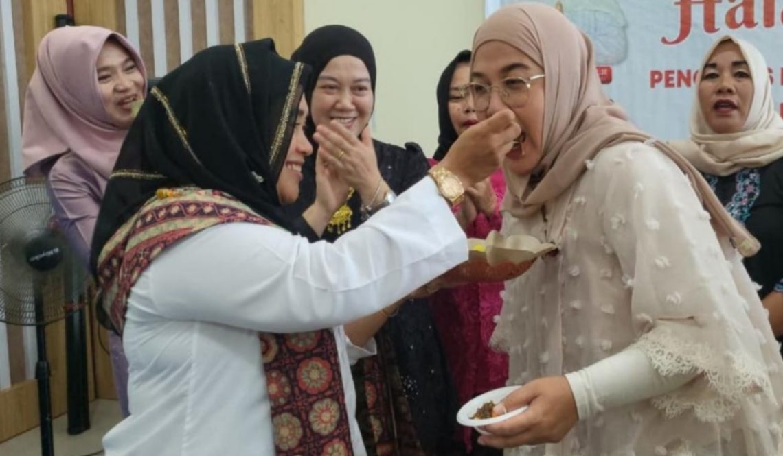 Ketua TP PKK Merangin Hj Lavita Syukur saat menerima suapan potong kue tumpeng di Gedung Pusat Layanan Usaha Terpadu (PLUT) Sungai Misang, Bangko. (Dok: Deni Satria Budi)