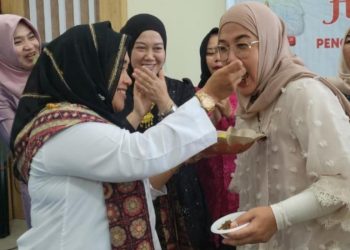 Ketua TP PKK Merangin Hj Lavita Syukur saat menerima suapan potong kue tumpeng di Gedung Pusat Layanan Usaha Terpadu (PLUT) Sungai Misang, Bangko. (Dok: Deni Satria Budi)