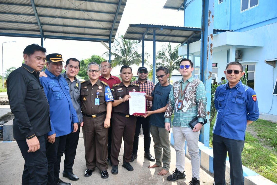 Petugas Kejati Jambi memasang garis penyitaan (line pidsus) di area pabrik PT PAL di Muaro Jambi. (Dok: Rahmat)