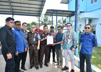 Petugas Kejati Jambi memasang garis penyitaan (line pidsus) di area pabrik PT PAL di Muaro Jambi. (Dok: Rahmat)