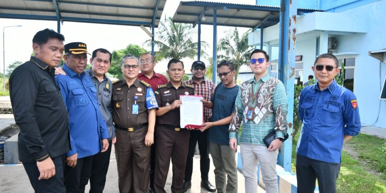 Petugas Kejati Jambi memasang garis penyitaan (line pidsus) di area pabrik PT PAL di Muaro Jambi. (Dok: Rahmat)