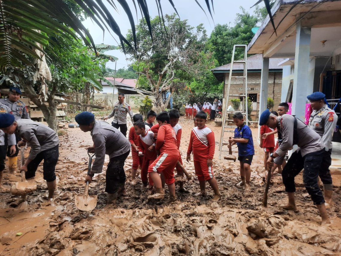 Personel Batalyon B Pelopor Satbrimob Polda Jambi membersihkan lumpur dan menyalurkan bantuan sembako kepada warga terdampak banjir di Desa Teluk Kecimbung, Sarolangun. (Dok: Alpin)