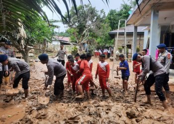 Personel Batalyon B Pelopor Satbrimob Polda Jambi membersihkan lumpur dan menyalurkan bantuan sembako kepada warga terdampak banjir di Desa Teluk Kecimbung, Sarolangun. (Dok: Alpin)