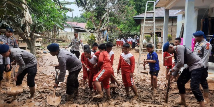Personel Batalyon B Pelopor Satbrimob Polda Jambi membersihkan lumpur dan menyalurkan bantuan sembako kepada warga terdampak banjir di Desa Teluk Kecimbung, Sarolangun. (Dok: Alpin)