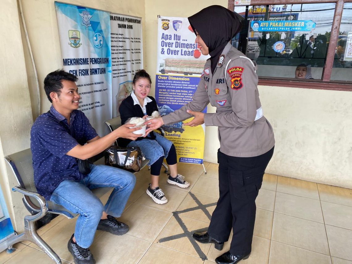Personel Sie STNK Subdit Regident Ditlantas Polda Jambi saat membagikan makanan gratis kepada wajib pajak, petugas SPBU, dan masyarakat dalam kegiatan Jumat Berkah di kawasan Samsat Kota Jambi, Jumat (22/5/2026). (Dok: Alpin)