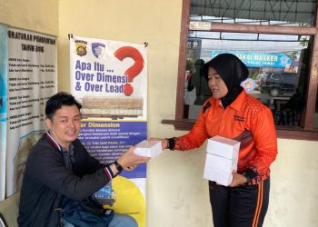 Personel Sie STNK Subdit Regident Ditlantas Polda Jambi membagikan makanan gratis kepada masyarakat dalam kegiatan Jumat Berkah di Samsat Kota Jambi, Jumat (5/6/2026). (Dok: Alpin)