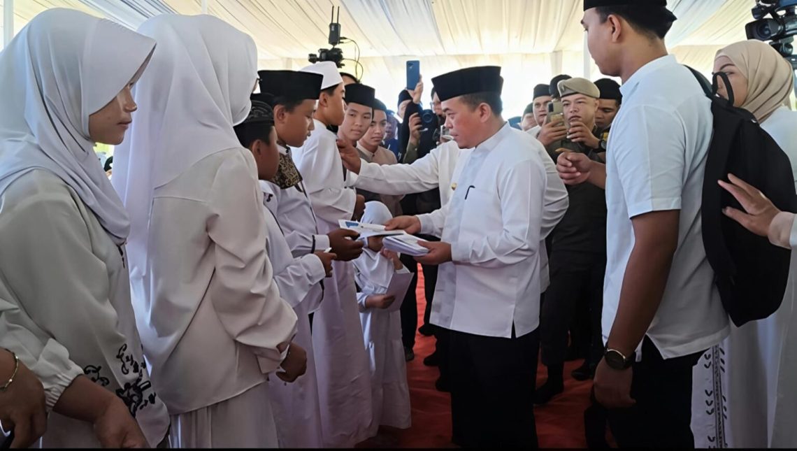 Gubernur Jambi Al Haris menyerahkan santunan kepada anak yatim pada kegiatan Lebaran Yatim dan Berbagi Kebahagiaan Bersama Anak Yatim di Lapangan Kantor Gubernur Jambi. (Dok: Rudi)