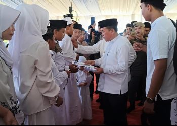 Gubernur Jambi Al Haris menyerahkan santunan kepada anak yatim pada kegiatan Lebaran Yatim dan Berbagi Kebahagiaan Bersama Anak Yatim di Lapangan Kantor Gubernur Jambi. (Dok: Rudi)