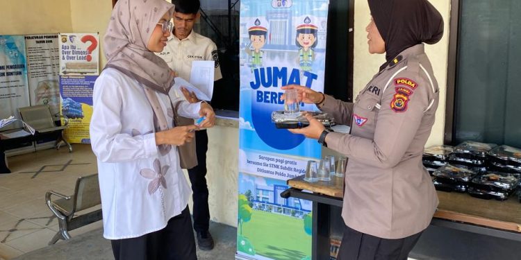 Personel Sie STNK Subdit Regident Ditlantas Polda Jambi dipimpin AKP Hadi Siswanto membagikan makanan gratis kepada wajib pajak di Samsat Kota Jambi dalam kegiatan Jumat Berkah, Jumat Berbagi, Jumat (26/6/2026). (Dok: Rudi)