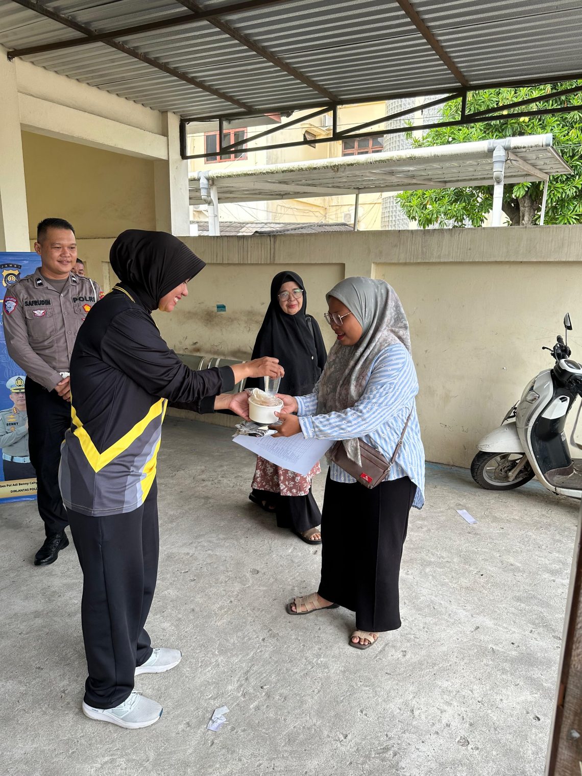 Personel Sie STNK Subdit Regident Ditlantas Polda Jambi membagikan makanan gratis kepada wajib pajak di Samsat Kota Jambi dalam kegiatan Jumat Berkah, Jumat Berbagi, Jumat (12/6/2026). (DOk: Alpin)