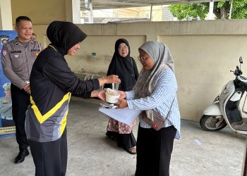 Personel Sie STNK Subdit Regident Ditlantas Polda Jambi membagikan makanan gratis kepada wajib pajak di Samsat Kota Jambi dalam kegiatan Jumat Berkah, Jumat Berbagi, Jumat (12/6/2026). (DOk: Alpin)
