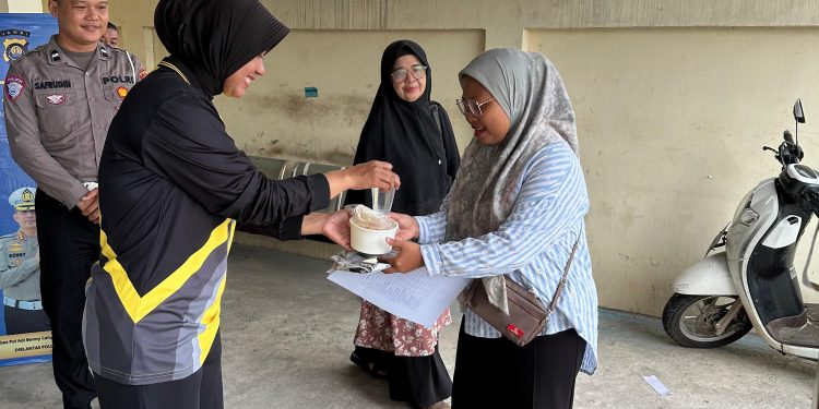 Personel Sie STNK Subdit Regident Ditlantas Polda Jambi membagikan makanan gratis kepada wajib pajak di Samsat Kota Jambi dalam kegiatan Jumat Berkah, Jumat Berbagi, Jumat (12/6/2026). (DOk: Alpin)