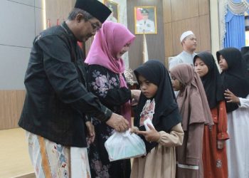 Bupati Tanjung Jabung Barat H. Anwar Sadat didampingi Ketua TP PKK Hj. Fadhilah Sadat menyerahkan santunan dan bingkisan kepada anak-anak yatim pada peringatan 10 Muharram 1448 Hijriah di Rumah Dinas Bupati. (Dok: Diskominfo Tanjab Barat)