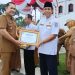 Bupati Merangin H M Syukur memberikan penghargaan usai memimpin upacara peringatan Hari Keluarga Nasional (Harganas) ke-33 di halaman Kantor Bupati Merangin. (Dok: Rahmat)